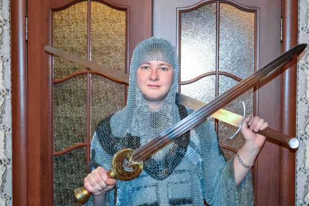 一个穿着骑士锁子甲的男人在自己的房间里。骑士手中的剑。图片下载