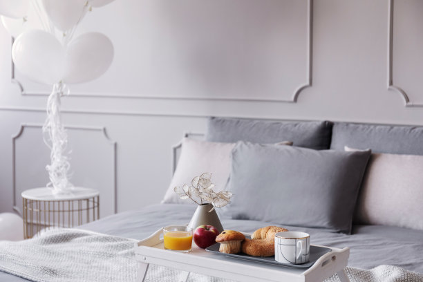 橙汁、苹果、松饼和咖啡摆放在时髦的灰色卧室内部，有一堆气球，真实的照片和拷贝空间图片下载