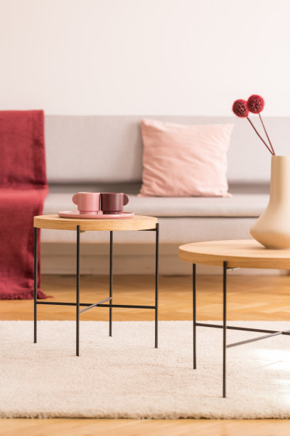 明亮的客厅内设有咖啡杯、花瓶和鲜花的咖啡桌，灰色的沙发，空白的白色墙壁上有真实的照片和复制空间图片下载