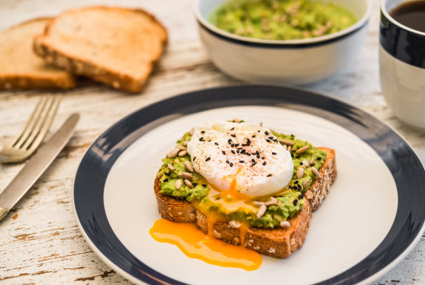 一张牛油果吐司配荷包蛋、芝麻和黑咖啡的食物照片。早餐、午餐、早午餐、晚餐便餐、素菜、健康饮食理念。图片下载