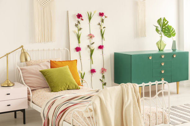 床上有橄榄绿、橘色和淡粉色的枕头，羽绒被和条纹毯子，时尚的卧室内部的真实照片，绿色的橱柜和花卉板图片下载