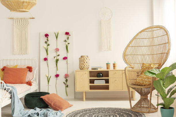 柳条孔雀椅与图案枕头在舒适的卧室内部与流苏在墙上，花板和木制橱柜，真实照片图片下载