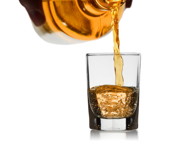 从一个玻璃瓶中流出的威士忌在一个小玻璃杯中图片下载