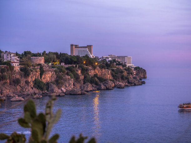 海面上淡紫色的日落天空。山脉和游艇图片下载