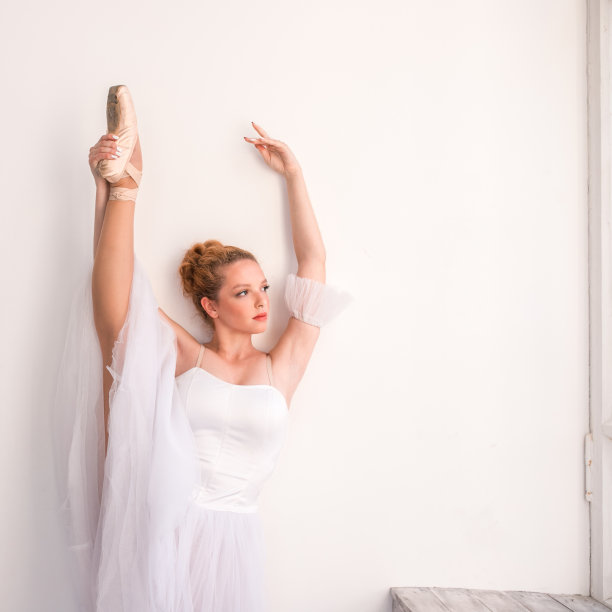 年轻优雅的芭蕾舞演员在白色的工作室跳舞。图片下载