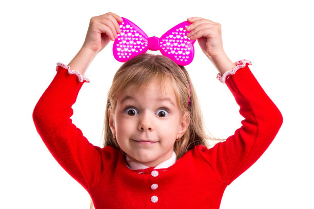 有趣的微笑金发女孩，瞪着眼睛，穿着红色的裙子，白色的孤立的背景上有一个粉红色的带蝴蝶结，手在蝴蝶结上。风景图片图片下载