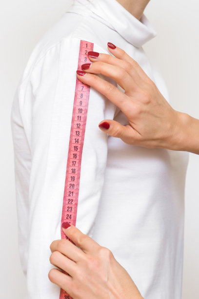 设计师的手用粉红色的卷尺测量苗条女子的手臂长度。身体的一部分。正确的大小。特写镜头。侧视图。图片下载