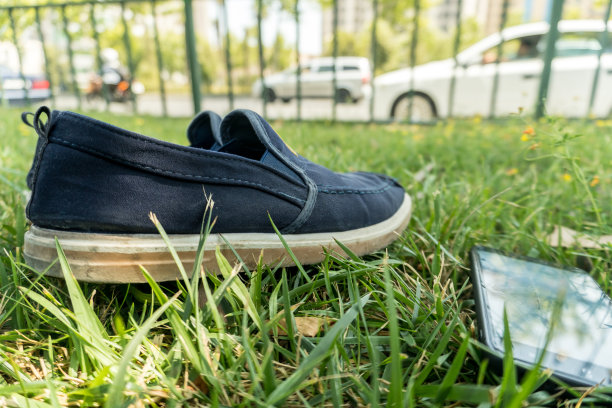 草地上的运动鞋和手机。图片下载