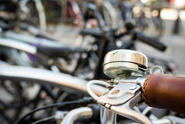 一个自行车把手和铃铛的特写，在城市中心的一个自行车停车场的不聚焦的背景。西班牙阿斯图里亚斯,希洪。图片下载