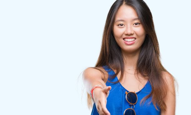 年轻的亚洲女人在孤立的背景微笑友好地提供握手作为问候和欢迎。成功的事业。图片下载