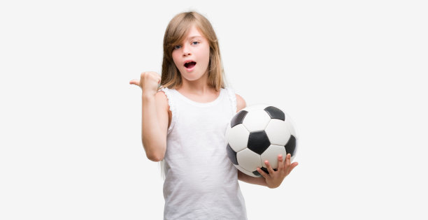 年轻的金发小孩拿着足球用手和手指向上指着幸福的脸微笑图片下载