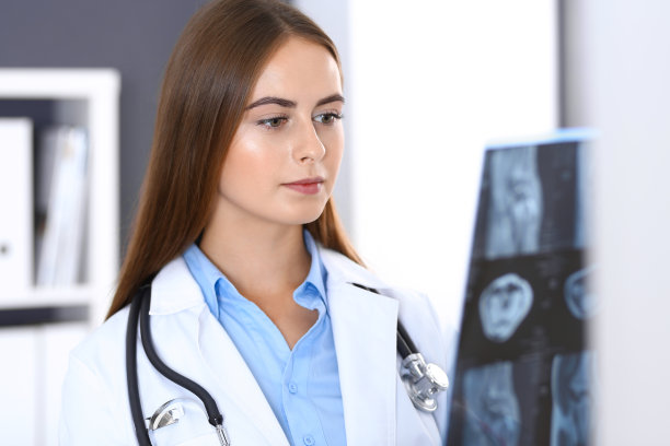 一位女医生站在医院窗户附近检查x光照片。在工作中的外科医生或整形外科医生医疗保健理念。图片下载