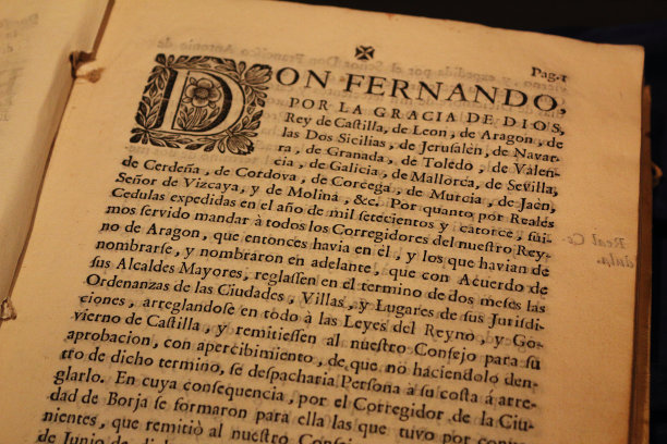 这是一本用西班牙语写的古书的特写，在一页发黄的厚纸上，在段落的开头有一个大大的微缩图图片下载