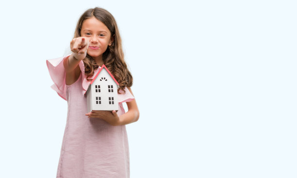深色头发的西班牙裔女孩拿着小房子，手指指向相机和你，手势，正面自信的手势图片下载
