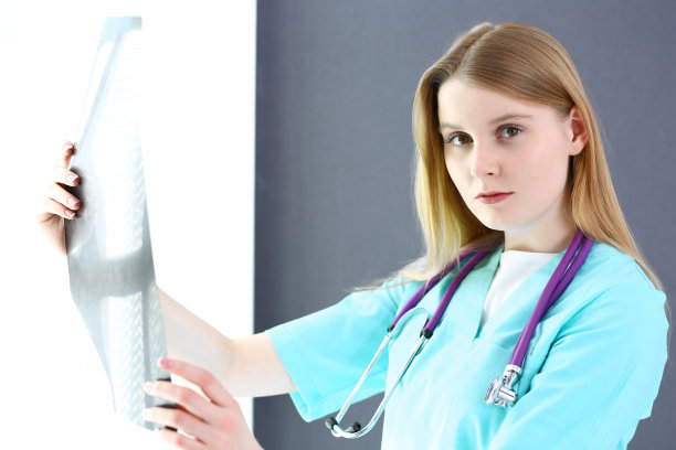 在诊所或医院，女医生站在窗边检查x光照片。医疗保健理念。医生在工作中。图片下载