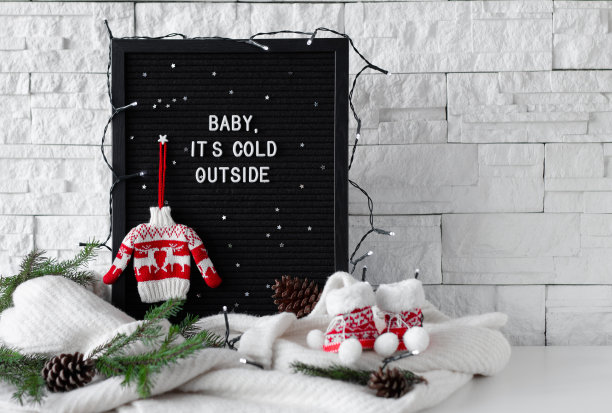 宝贝，外面很冷，用白色字母写在黑板上，用针织毛衣，针织袜子和杉木树枝在白色的背景上图片下载