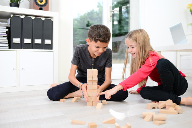 两个快乐的小弟弟和小妹妹一起在家里玩着木砖玩具游戏图片下载
