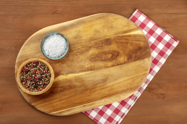 一张带有盐和胡椒的木质砧板的照片，用格子布从顶部拍摄，背景是黑色的乡村风格，并留有文字的地方。有拷贝空间的烹饪架图片下载