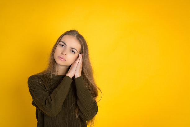 照片美丽的年轻可爱的女人摆孤立在黄色背景睡觉。图片下载