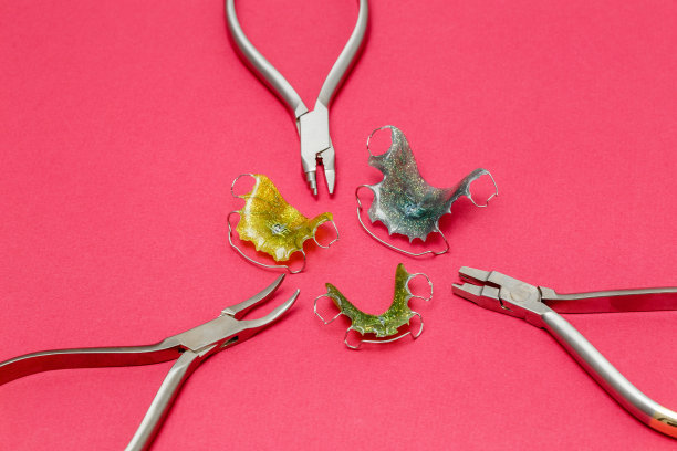 牙齿矫正的金属工具和牙套或固位体，粉红色背景图片下载