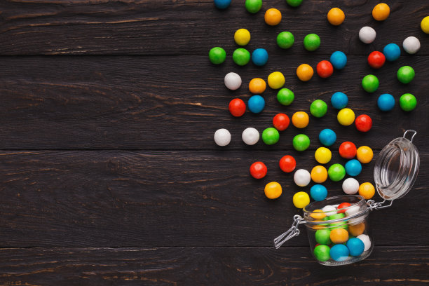 木制背景上有彩色糖果的玻璃罐子图片下载
