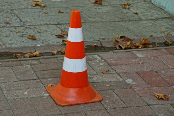 街道上的人行道上立着一个带有条纹的塑料锥形路标图片下载