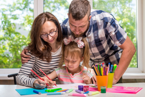 妈妈和爸爸帮助他们的小女儿做学校的家庭作业图片下载