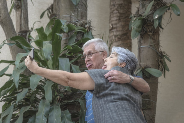 成熟的成人夫妇拥抱，展示舌头，用手机自拍图片下载