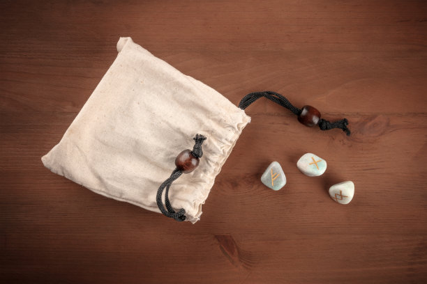 这是一张古代北欧符文的照片，来自Futhark字母表，石头上的符号用于巫术和其他魔法和占卜，从一个袋子里扔出来，背景是黑色的，有文字的地方，从顶部拍摄图片下载