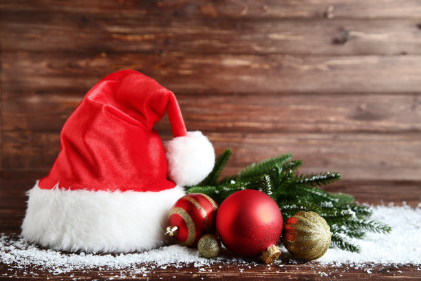 圣诞老人的帽子与小装饰品和冷杉树枝在木制的桌子上图片下载