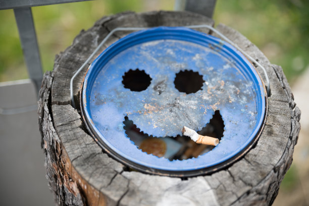 在一个笑着的蓝色烟灰缸上捏着香烟图片下载