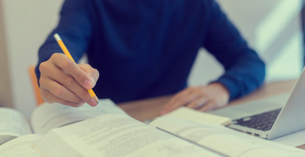 在大学图书馆安静的区域，用黄色铅笔写作业和研究项目的人的手，国际学生和教育日的概念图片下载