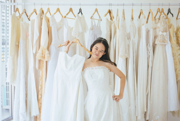 亚洲少女新娘试穿婚纱，女设计师在婚纱店做调整图片下载