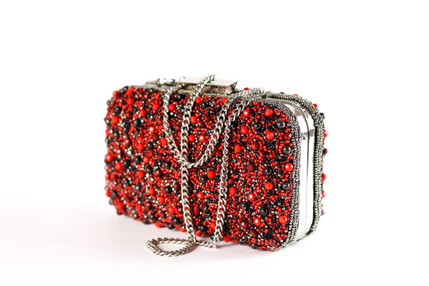 一个布满石头的红色小女性手提包。离合器。关闭了。孤立在白色背景上。图片下载