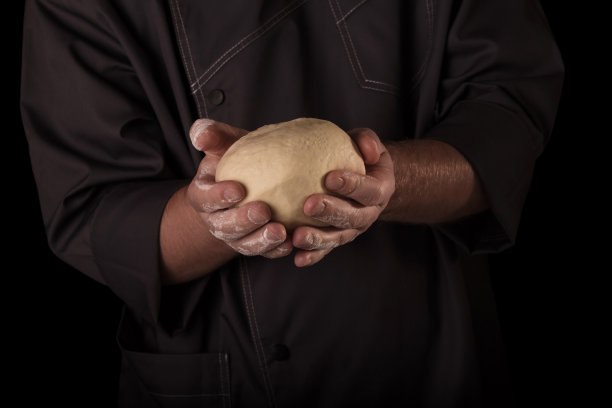 松软的酵母面团在厨师手中孤立在黑色背景上图片下载