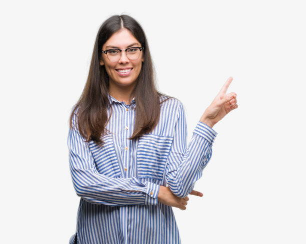年轻美丽的西班牙女商人脸上带着大大的微笑，用手和手指指着一边看着镜头。图片下载