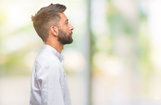 成年西班牙男子在孤立的背景看向一边，放松的侧面姿势与自然的脸自信的微笑。图片下载