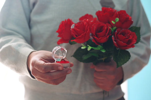 一个男人手里拿着一束美丽的花束和结婚戒指图片下载