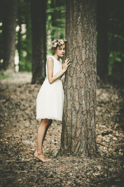 少女倚在一棵大树上，头上戴着花圈，人像图片下载