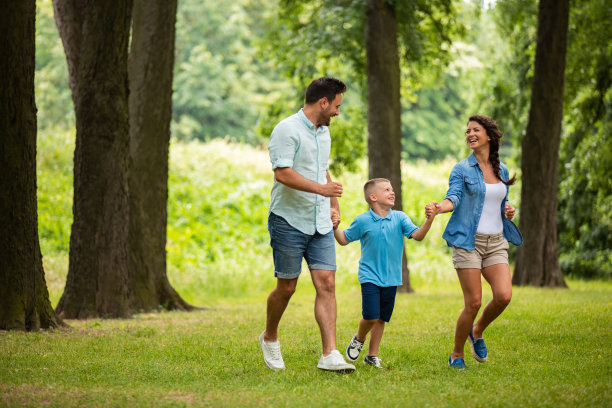 年轻幸福的家庭手牵着手穿过公园图片下载
