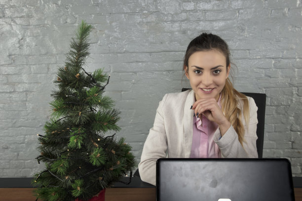 年轻漂亮的女商人，圣诞节时坐在桌子后面图片下载