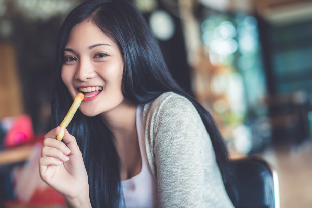 年轻漂亮的亚洲女人早上在咖啡店或咖啡厅吃零食。复古暖色调的图像。图片下载