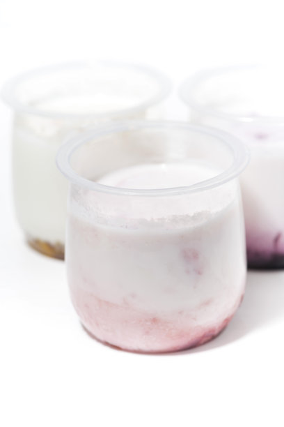 白色背景上有水果添加剂的酸奶，垂直排列图片下载