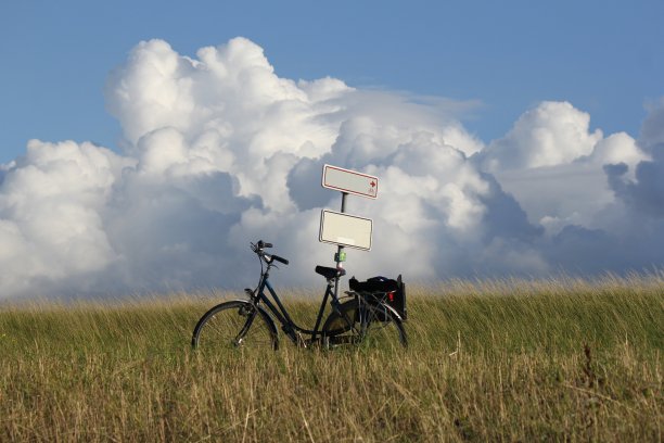 一辆自行车在草地之间的户外，蓝天和大白云图片下载