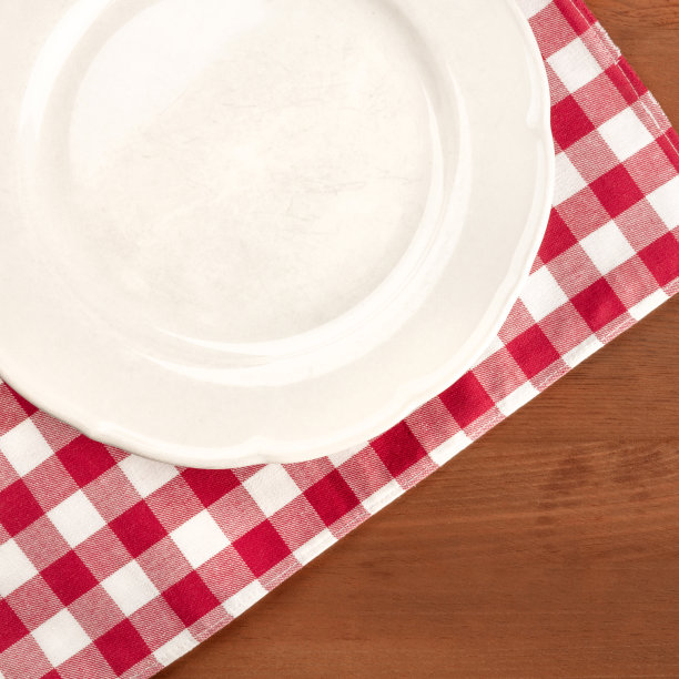 一个白色盘子上的维希图案布的特写，在一个黑色的乡村木桌与复制空间图片下载