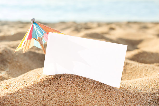 空白卡片与装饰小伞在沙滩沙滩。图片下载
