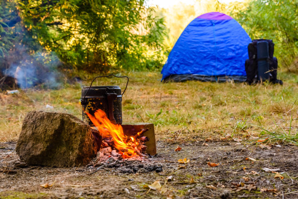 用水壶在篝火上煮食物。帐篷的背景图片下载