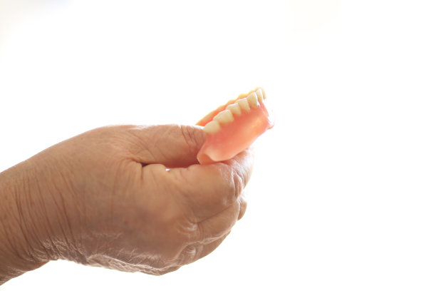女人的手拿着假牙的特写图片下载