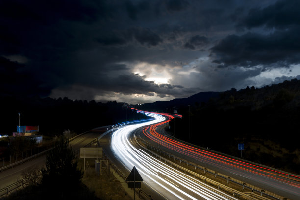 西班牙巴塞罗那省的高速公路上有交通灯的痕迹和地平线上的风暴图片下载