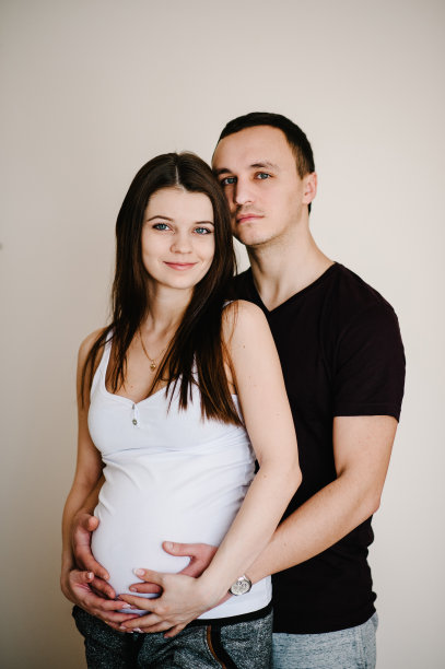 丈夫站着，抱着怀孕妻子的肚子。女人，女孩和可爱的帅哥在家抱着肚子。爱的夫妻。亲子关系的概念。婴儿洗澡。家庭照片。图片下载